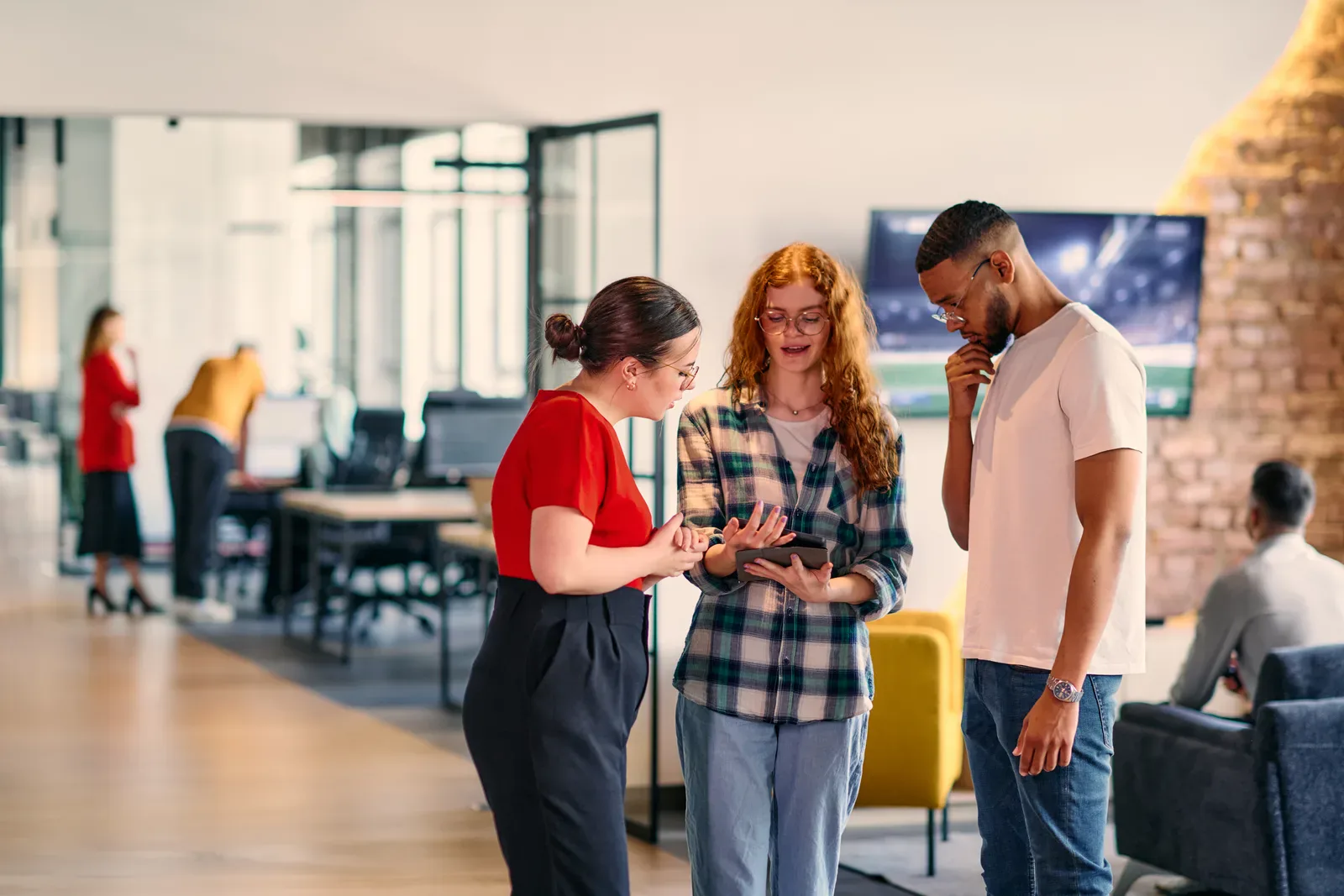 Tre personer diskuterer et prosjekt i et lyst kontorfellesskap